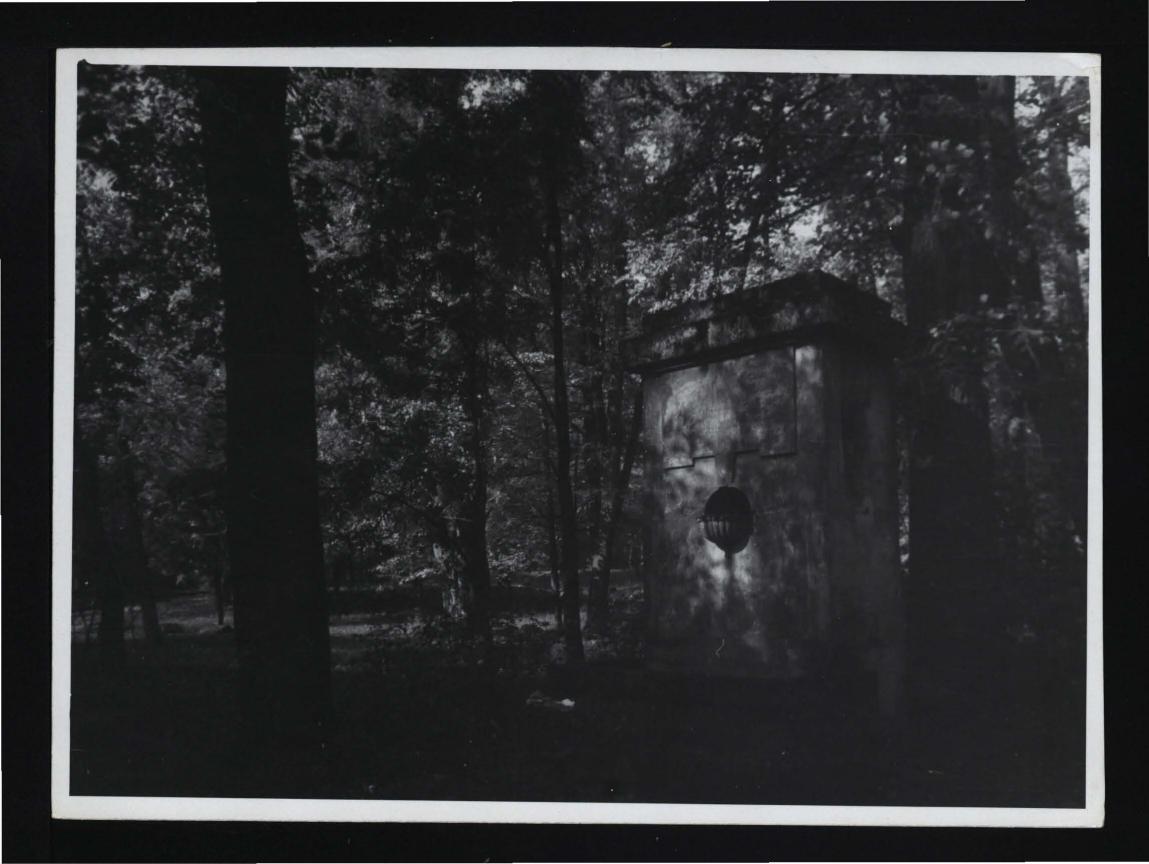 fotografia czarno-biała przedstawiająca murowaną budowlę przy miejscowym parku, skan 1