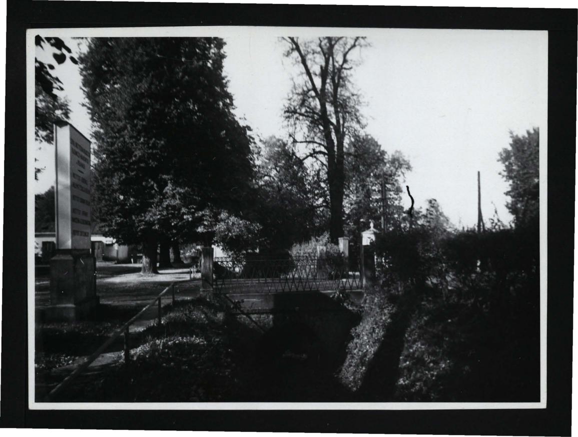 fotografia czarno-biała przedstawiająca mostek nad fosą przy miejscowej posesji, skan 1