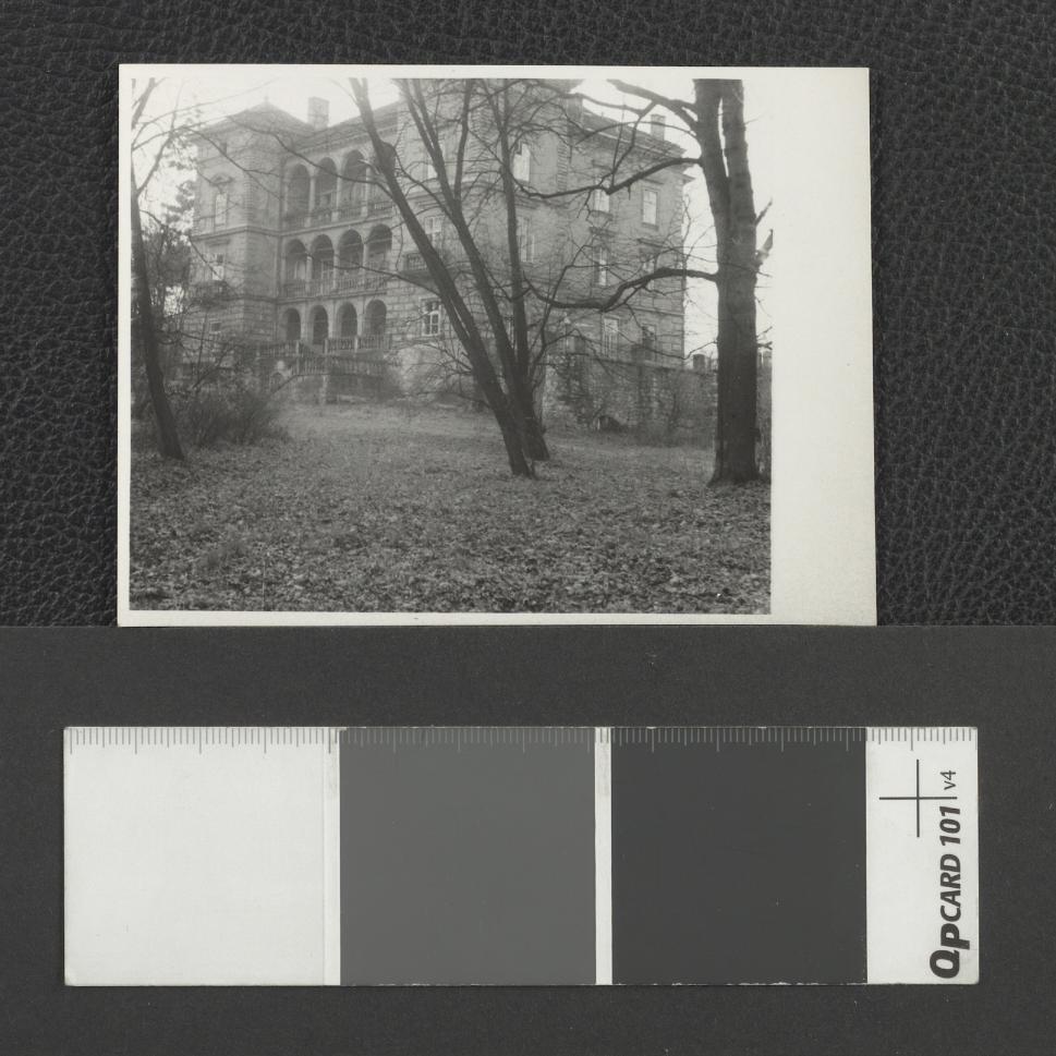 fotografia czarno-biała, luzem, fotografia przedstawia Willę Decjusza w Woli Justowskiej. Na pierwszym planie sylwety bezlistnych drzew. Dopisek odręczny na rewersie fotografii: „Wola Justowska”, skan 1