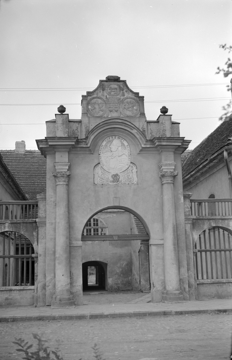 Kolegium z alumnatem. Brama prowadząca na dziedziniec, po obu stronach kolumny. Na portalu widnieje popiersie króla Stanisława Augusta Poniatowskiego z kartuszem w obramowaniu., skan 1