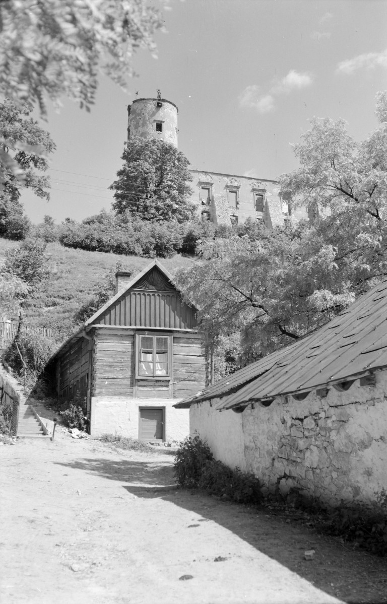 Zamek. Zniszczone fragment murów. Fragment elewacji płd. z basztą. Renesans. Poniżej zabudowa miejska w postaci drewnianego domu z dachem dwuspadowym. , skan 1