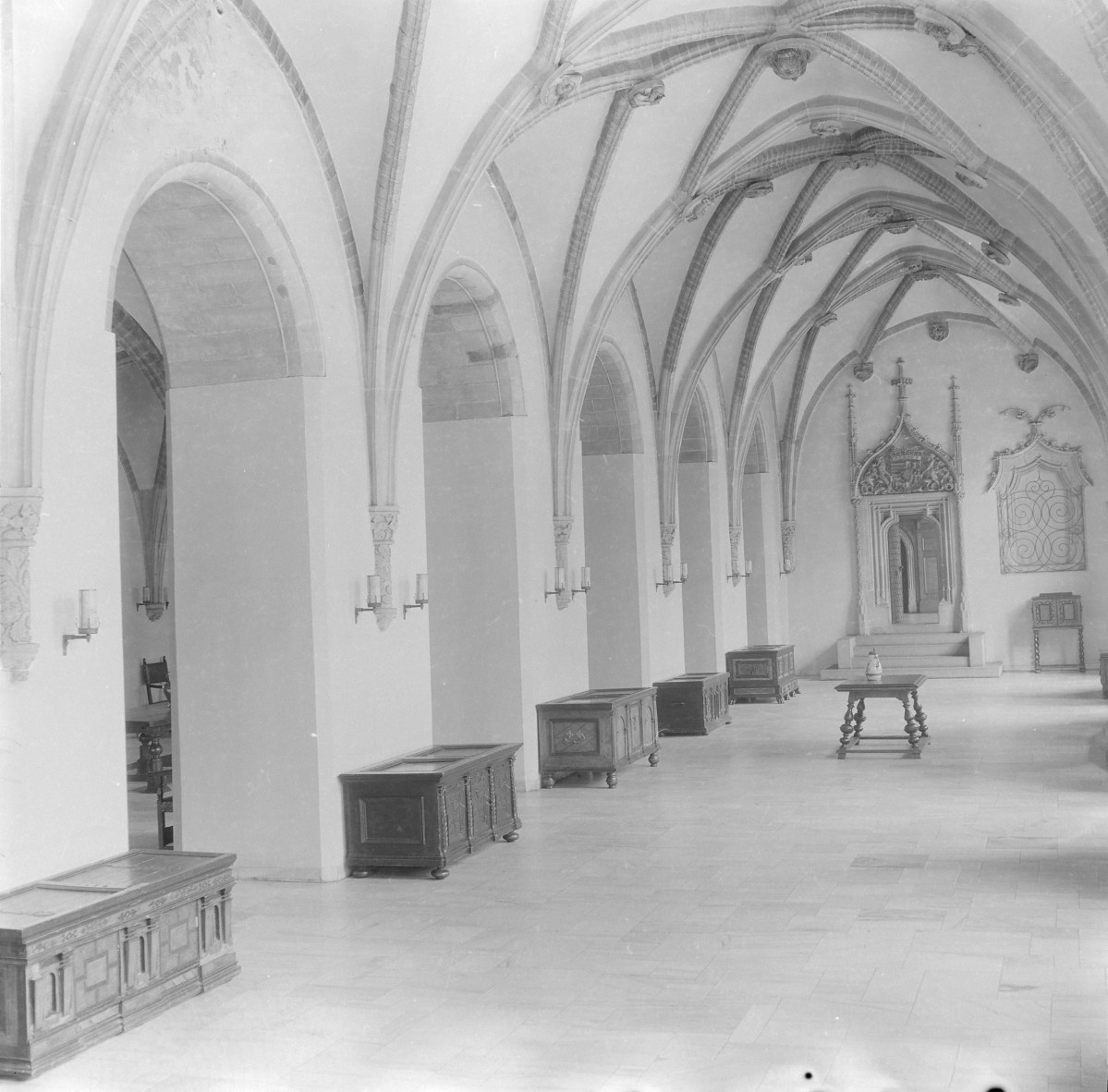 Stary Ratusz. Wnętrze Wielkiej Sali. Skrzydło dawnego reflektarza. Filary przy których stoją skrzynie. Widoczne służki oraz sklepienie gwiaździste. W oddali portal z herbem Macieja Korwina., skan 1