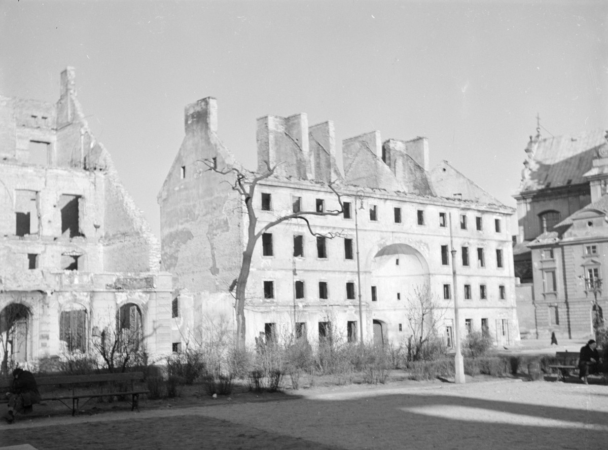 Zajazd "Dziekanka". Widok ogólny. Zniszczony dach z widocznymi kominami. Olbrzymia łukowata nisza w, której znajduje się brama wjazdowa. Obok zniszczona kamienica. , skan 1
