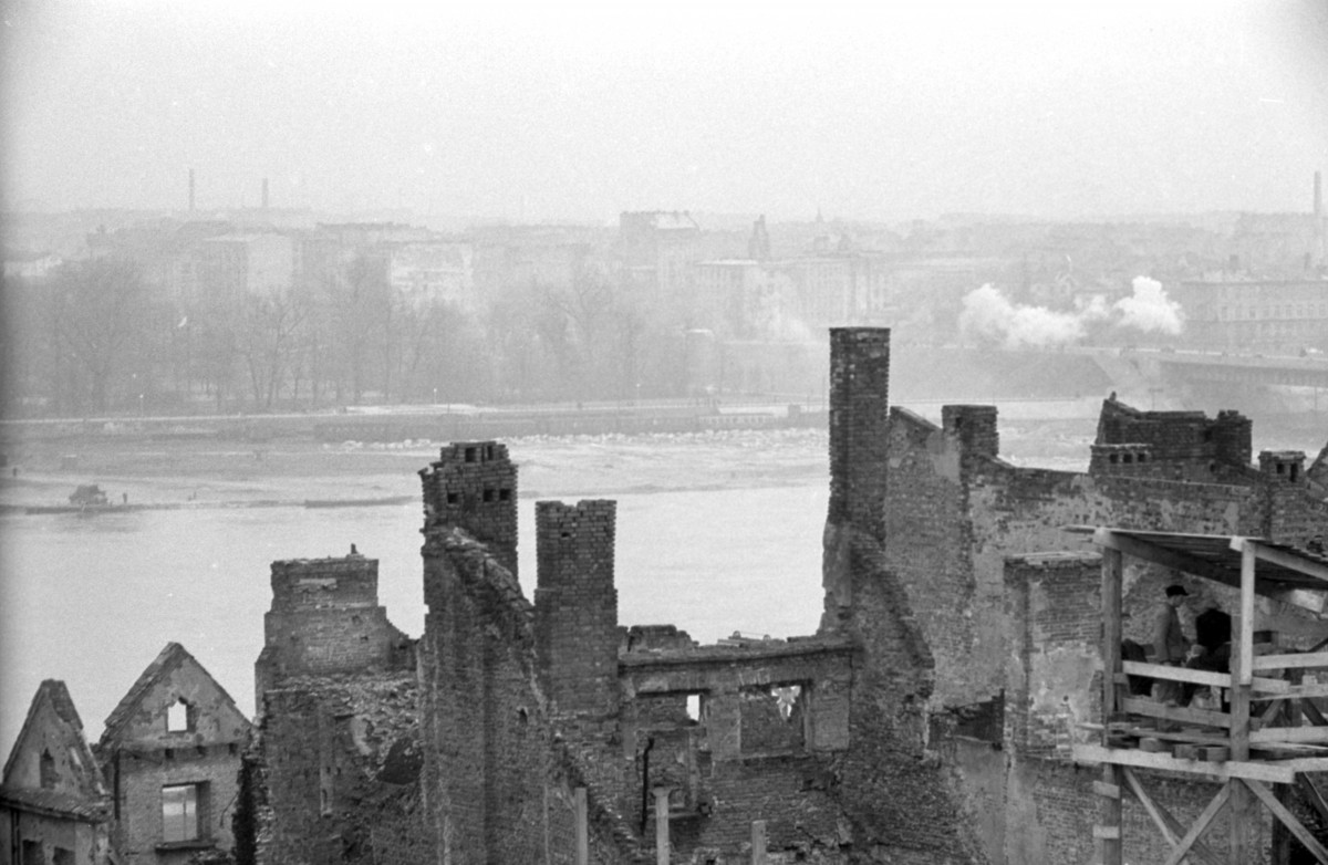 Widok z dachu kamienicy Baryczkowskiej. Widoczne fragmenty ruin a po prawej stronie rusztowanie z pracownikami. W oddali panorama Pragi., skan 1