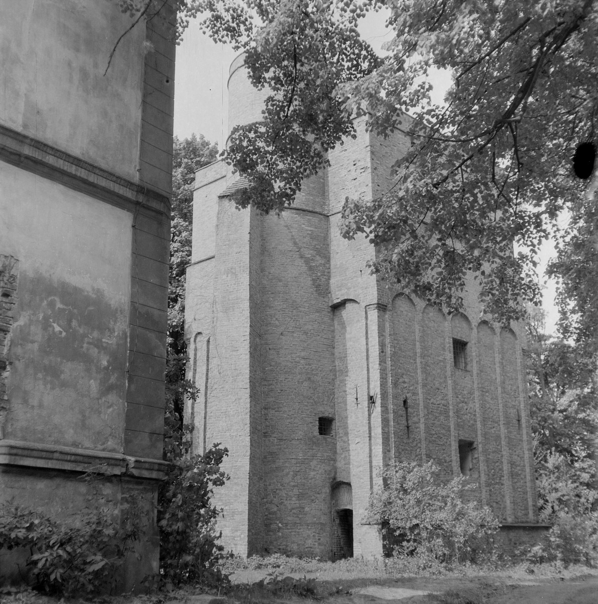 Zamek. Fragment zabudowy. Baszta zamkowa. Obiekt wzniesiony jest z cegły i ma charakter obronny, co podkreślają grube mury oraz niewielkie, wąskie otwory okienne rozmieszczone nieregularnie w elewacjach. Widoczny jest niewielki, półkoliście zamknięty otwór wejściowy oraz małe okienka o charakterze strzelniczym, osadzone wysoko nad poziomem terenu. Elewacje artykułowane są pionowymi lizenami przechodzącymi w górnej części w rytmiczny ciąg ślepych arkad o półkolistym wykroju. Ten motyw arkadkowy nadaje górnej partii baszty dekoracyjny charakter. , skan 1