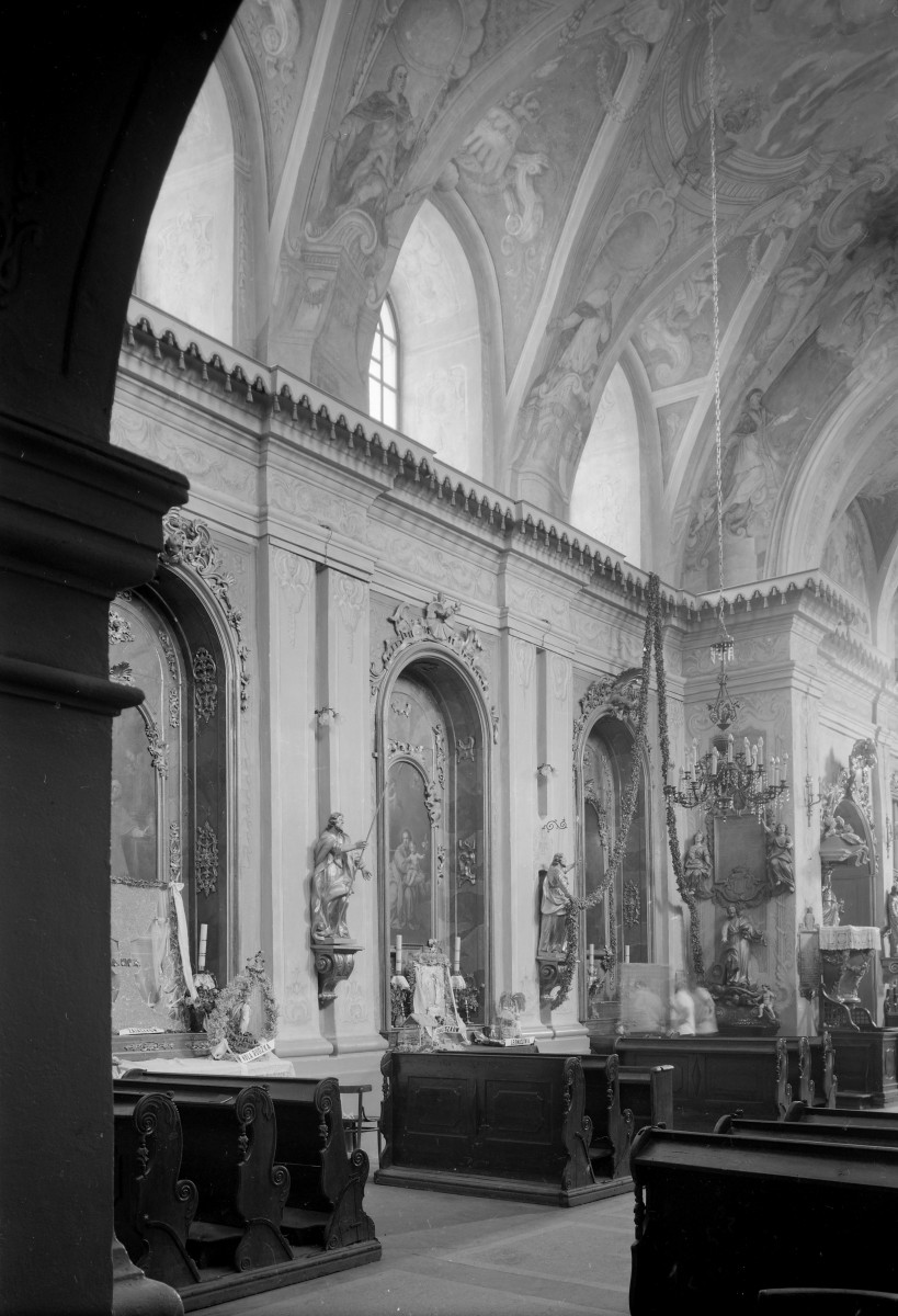Kościół Wniebowzięcia NMP - wnętrze: nawa boczna z ołtarzami bocznymi, pomiędzy nimi figury świętych, sklepienie ozdobione polichromią, skan 1