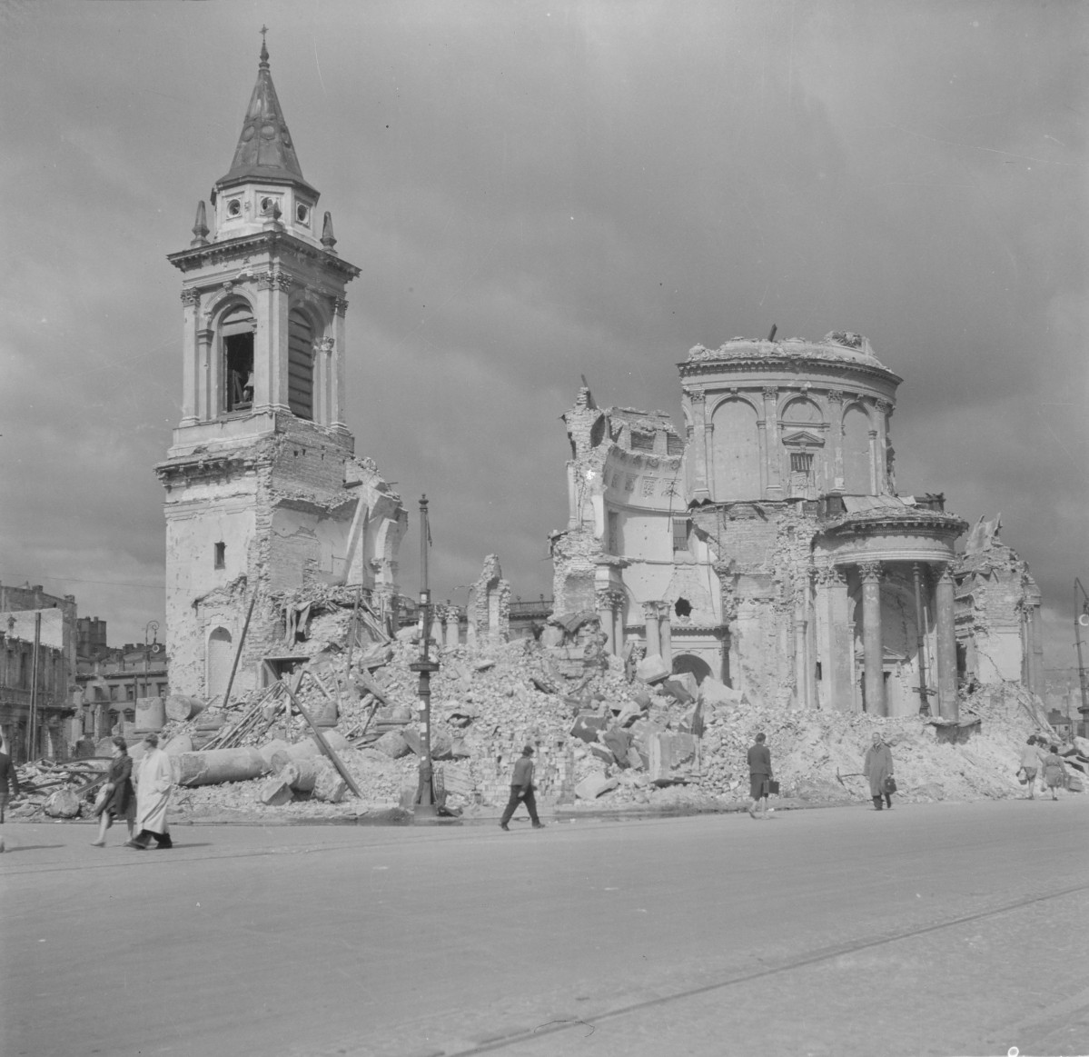 Kościół św. Aleksandra. Główna część budowli ma formę rotundy, której ściany artykułowane są pilastrami i półkolumnami oraz zwieńczone wyraźnym gzymsem koronującym. W elewacji rotundy znajdują się wysokie, półkoliście zamknięte wnęki okienne i arkady, typowe dla klasycyzującej kompozycji. Część murów rotundy została zniszczona, przez co widoczny jest przekrój konstrukcji ścian oraz fragmenty wewnętrznej struktury budynku. Od frontu do rotundy przylega portyk kolumnowy. Zachowały się fragmenty kolumn o klasycznych proporcjach oraz części belkowania. Po lewej stronie znajduje się wolnostojąca wieża dzwonnicza. Ma ona formę kilkukondygnacyjnej konstrukcji o klasycystycznej kompozycji. Dolna część wieży ma prostokątny rzut i jest masywna, natomiast wyższa kondygnacja jest przepruta dużymi arkadowymi otworami dzwonowymi. Naroża wieży są akcentowane pilastrami, a powyżej znajduje się profilowany gzyms. , skan 1