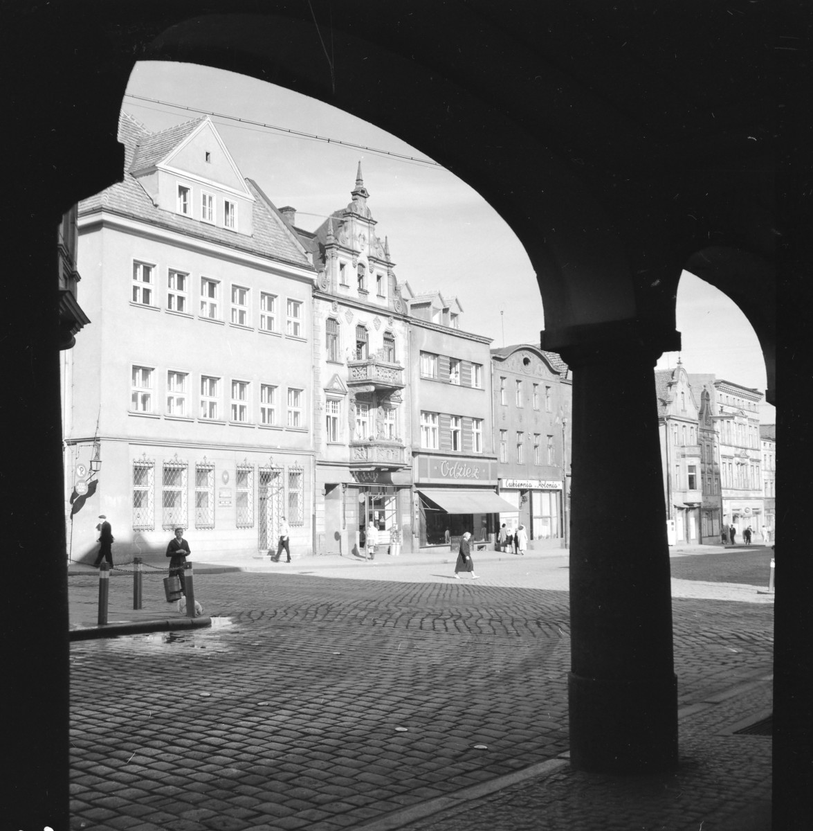 rynek miejski - fragment pierzei zachodniej - widok spod filarów kamienicy narożnej przy ul. Pod Filarami 2-4, skan 1