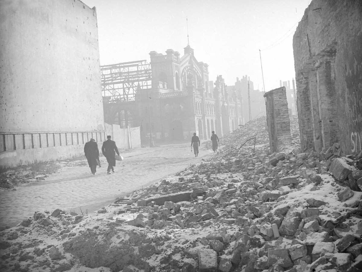 Zniszczona zabudowa miejska. Widok na elewacje frontową Hali Mirowskiej., skan 1