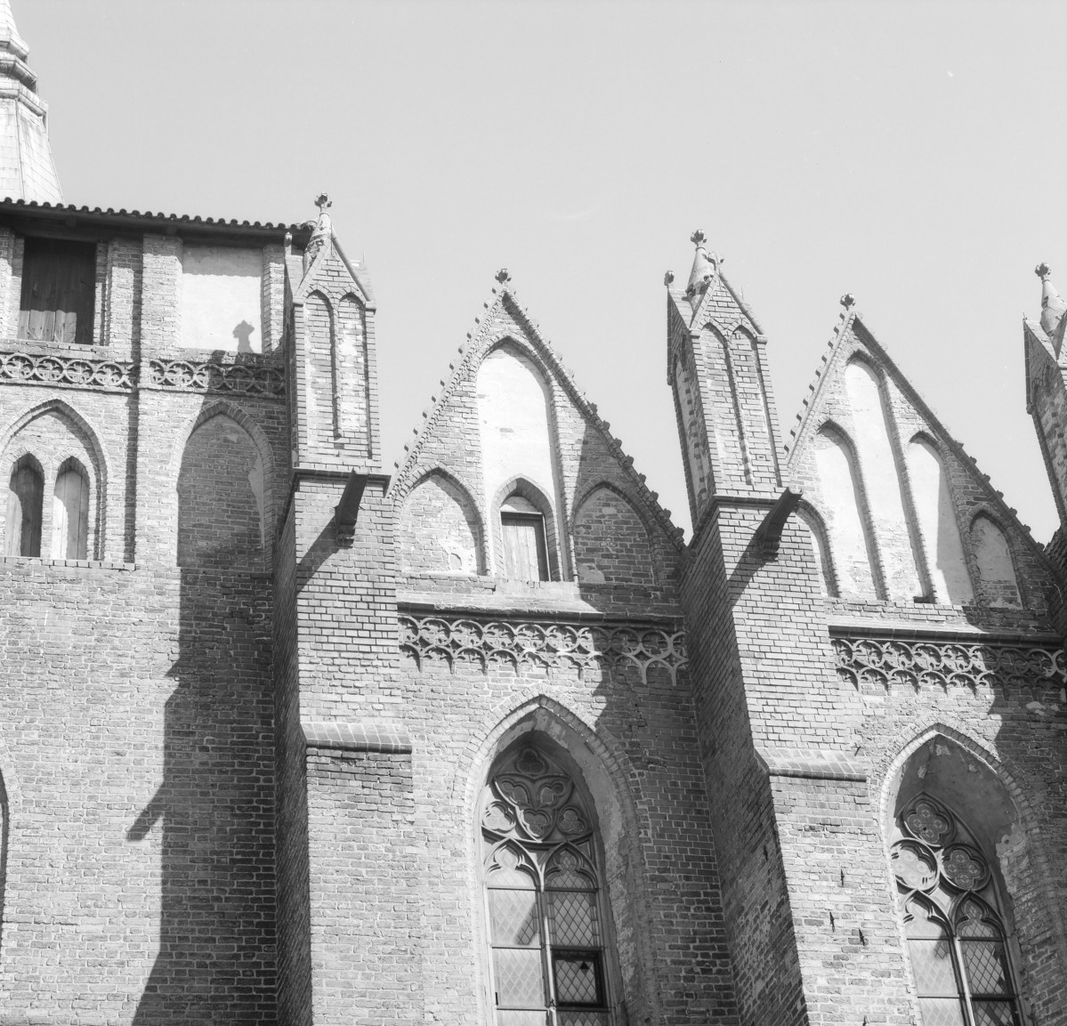 Kościół Wniebowzięcia Najświętszej Maryi Panny - fasada nawy. Wydatne skarpy przy korpusie zwieńczone pinaklami. Otwory okienne w typie maswerk. Rzygacze., skan 1