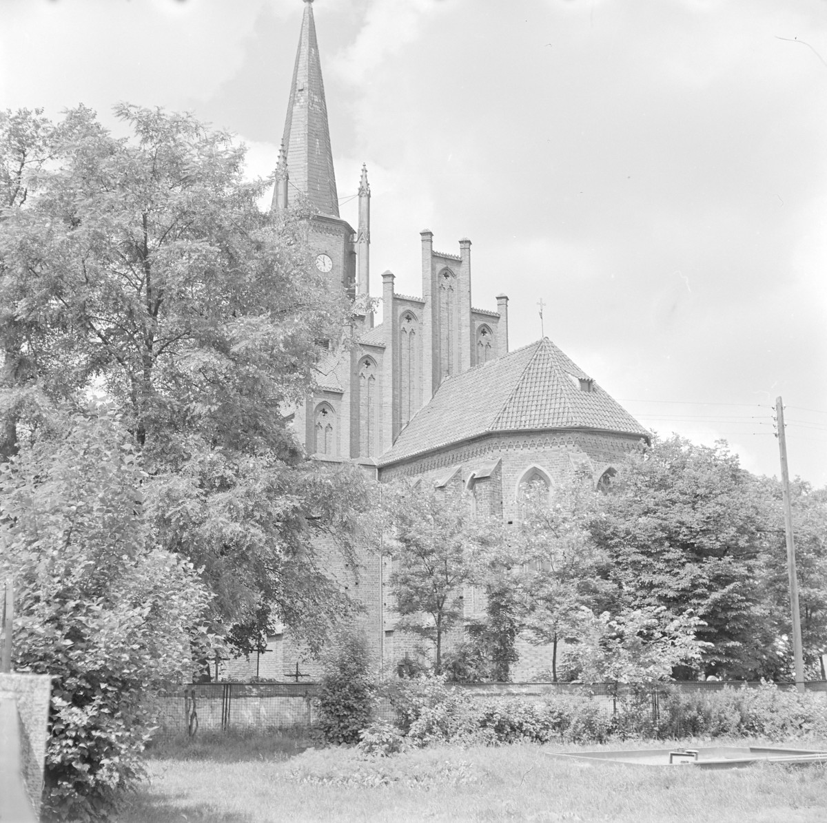 Kościół pw. Wniebowzięcia NMP - widok ogólny od wschodu. Elewacja prezbiterium z widocznymi przyporami. Szczyt schodkowy., skan 1