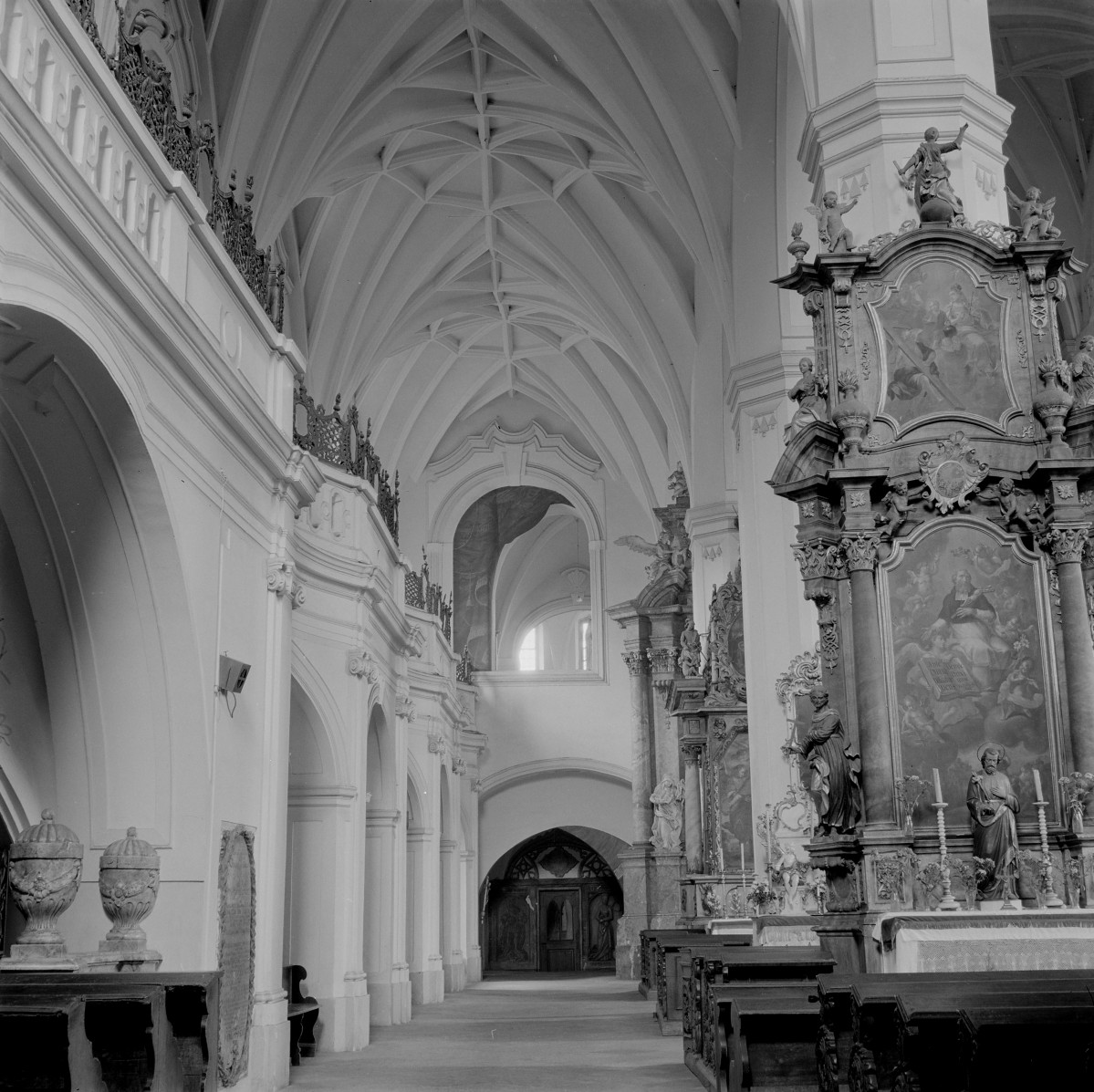 Kościół WNMP. Wnętrze. Ostrołukowe arkady otwierają się na nawę główną, a przestrzeń przykrywają sklepienia krzyżowo-żebrowe. Po prawej stronie znajduje się okazały ołtarz boczny o rozbudowanej strukturze architektonicznej, flankowany kolumnami i pilastrami, z obrazem w polu głównym oraz rzeźbami świętych ustawionymi na konsolach. Zwieńczenie ołtarza tworzą dynamiczne formy wolutowe oraz figury aniołów. , skan 1