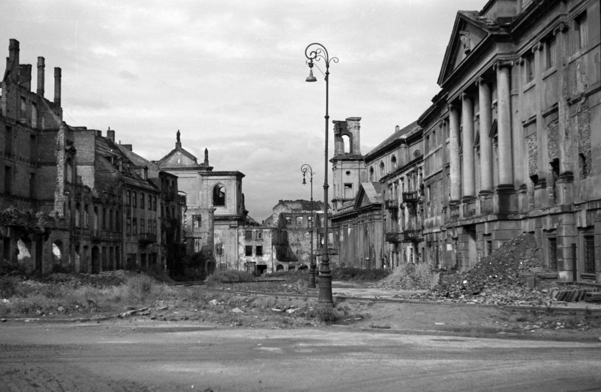 Widok od strony ul. Długiej. Skrzyżowanie z ul. Kilińskiego. Widoczne tory prowadzące na ulicę Kilińskiego. Po prawej stronie widoczny zniszczony budynek Archiwum Główne Akt Dawnych. Nieco dalej po tej samej stronie zniszczona elewacja i wieżyczka kościoła Ducha Świętego. Po lewej stronie nieco dalej fragment kościoła Dominikanów., skan 1