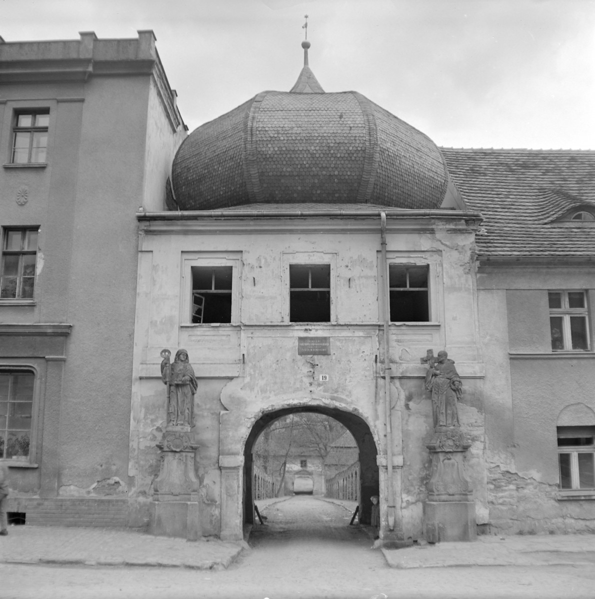 Brama przejazdowa oraz spichrz z baniastym hełmem. Figury świętych obok bramy. , skan 1