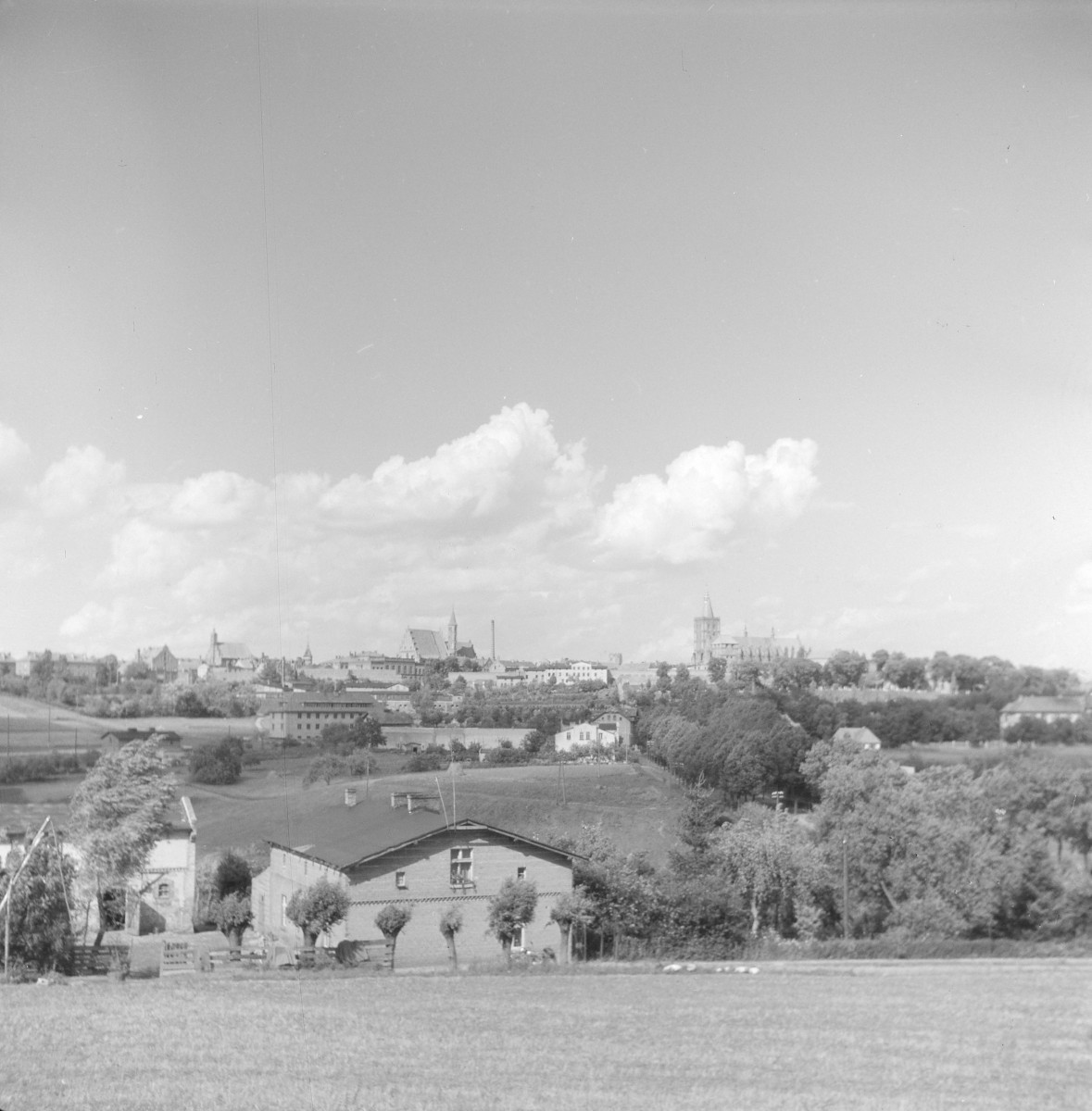 Panorama miasta od strony płn. Widoczne: wieża ciśnień, kościół archiprezbiterialny oraz kościół pofranciszkański. Poniżej zabudowa miejska., skan 1
