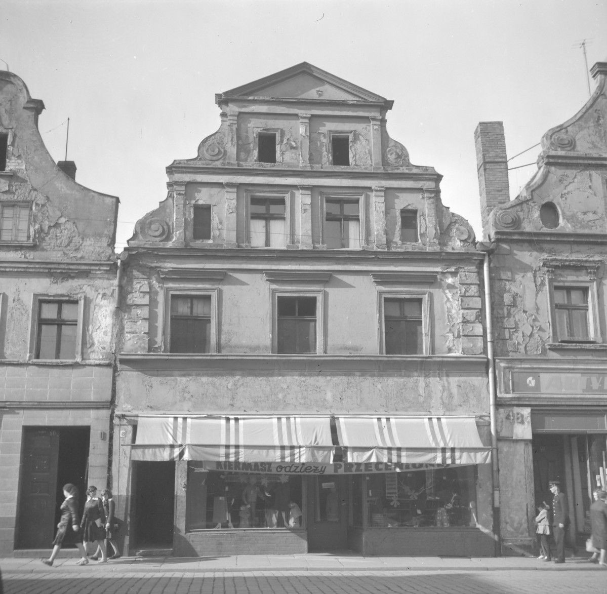 Zabudowa miejska. Elewacja frontowa kamienicy. Renesansowy szczyt. Mieszkańcy. Witryna sklepu odzieżowego. , skan 1