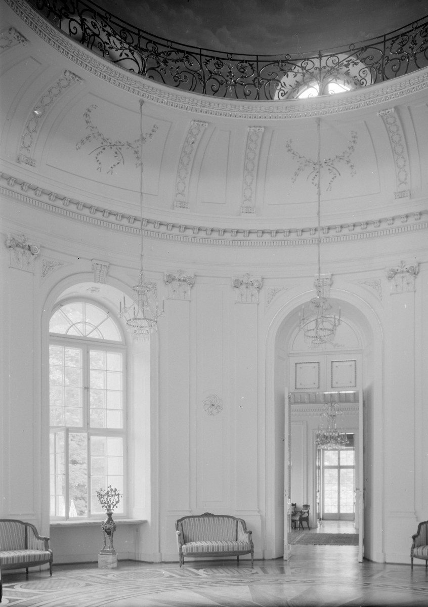 Palac - wnętrze: salon okrągły zw. biały. Meble i widoczne pilastry. Dekor., skan 1