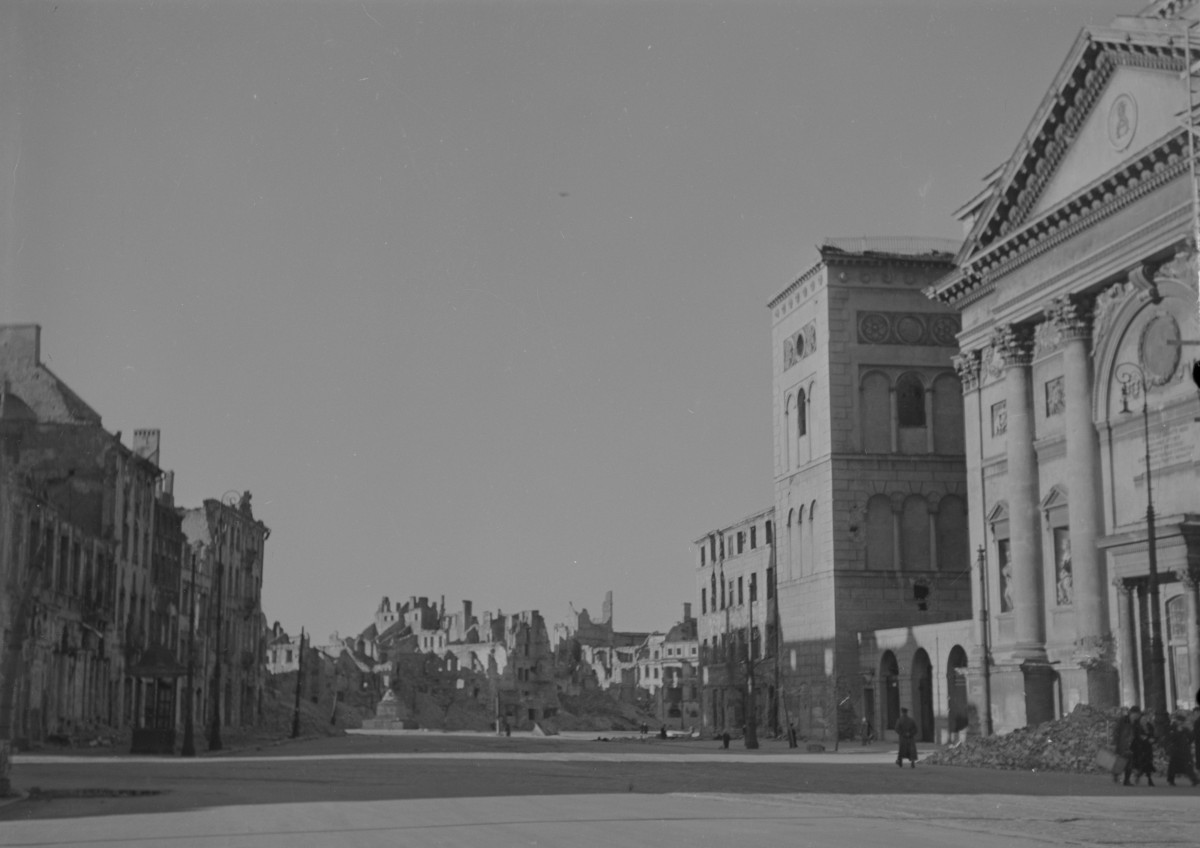 Oś widokowa w kierunku placu Zamkowego. Widoczne zniszczone kamienice Starego Miasta. Po prawej stronie fragment elewacji frontowej kościoła św. Anny oraz dzwonnica. Zniszczona kolumna Zygmunta. Gdzie nie gdzie mieszkańcy. , skan 1