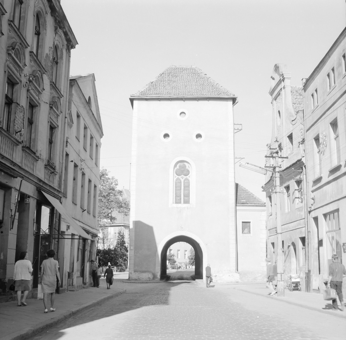 Brama Grudziądzka. Widok ogólny. Brama miejska wjazdowa. Przejazd łukowy oraz widoczny maswerk. Po obi stronach elewacje kamienic i mieszkańcy., skan 1