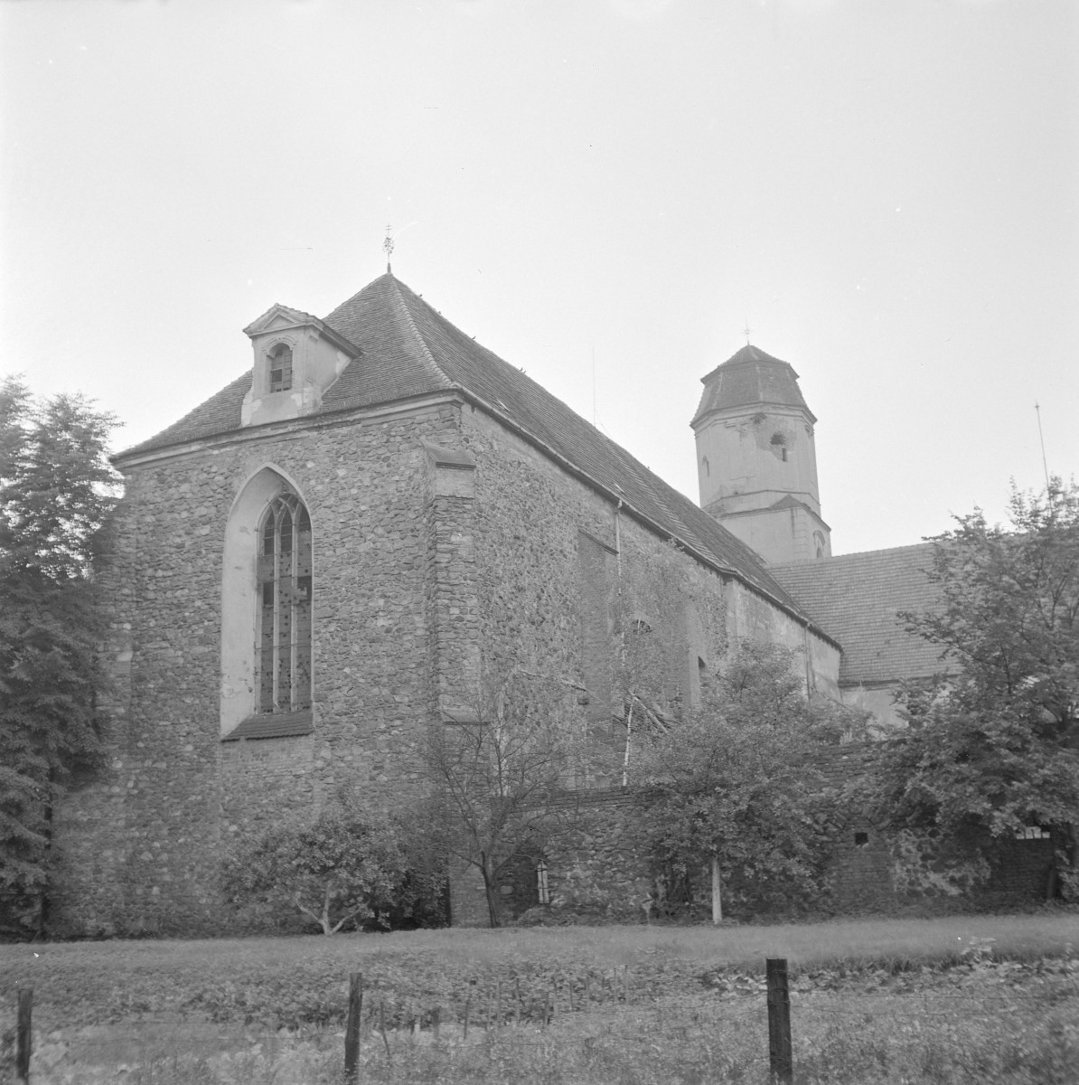 Kościół św. Piotra i Pawła. Charakter gotycki i wzniesiona została z kamienia polnego. Prezbiterium zamknięte jest prostą, trójkątną ścianą szczytową, w której umieszczono wysokie, ostrołukowe okno z maswerkiem. Korpus kościoła przykrywa stromy, dwuspadowy dach kryty dachówką ceramiczną. W połaci dachu widoczna jest niewielka lukarna o barokowym lub późniejszym wykroju. W tle wznosi się wieża o jasnych, tynkowanych elewacjach i prostym, hełmowym zwieńczeniu – stanowiąca późniejsze przekształcenie bryły, kontrastujące materiałowo z kamiennymi murami nawy., skan 1