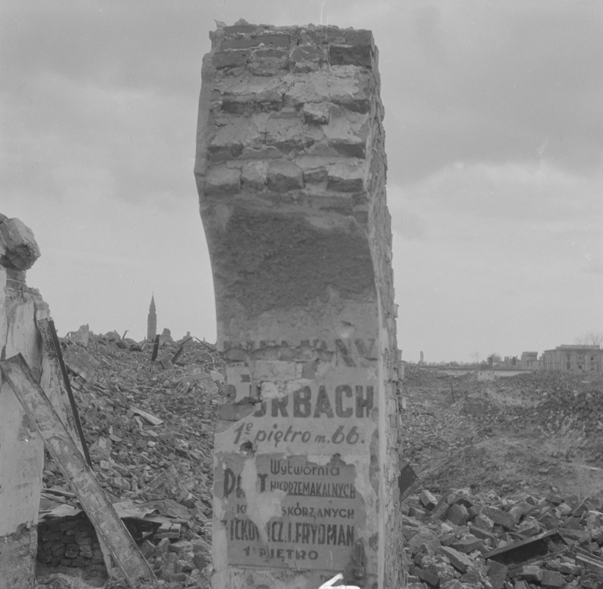Gruzowisko zabudowy ul. Nalewki. Fragment ruiny służący za słup ogłoszeniowy. Po lewej stronie w oddali kościół św. Augustyna., skan 1