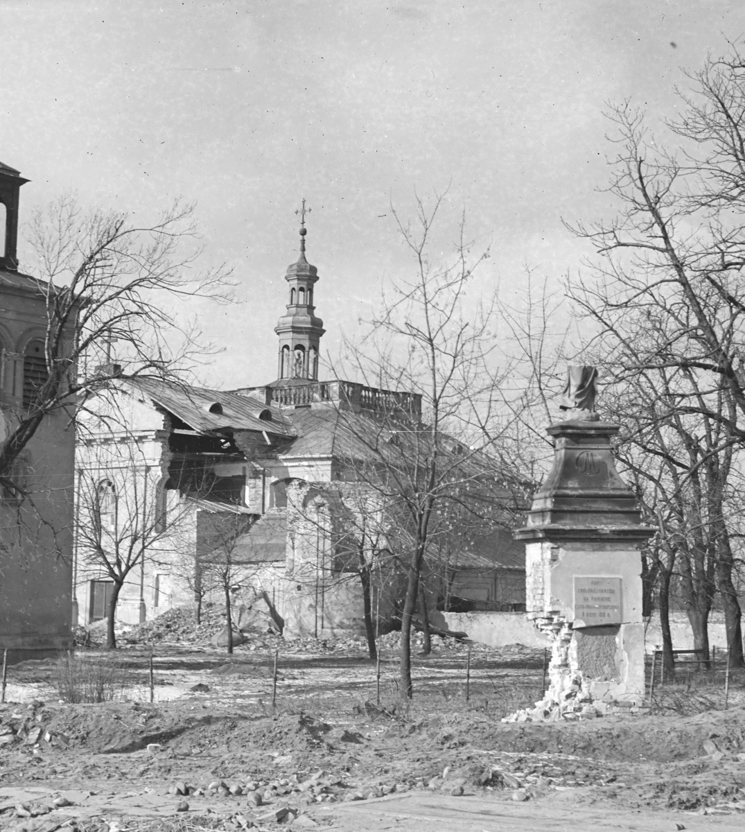 Kościół Matki Bożej Loretańskie - fragment elewacji i widoczna wieża z sygnaturką. Na pierwszym planie zniszczony pomnik z figurą Matki Bożej Królowej Narodu., skan 1