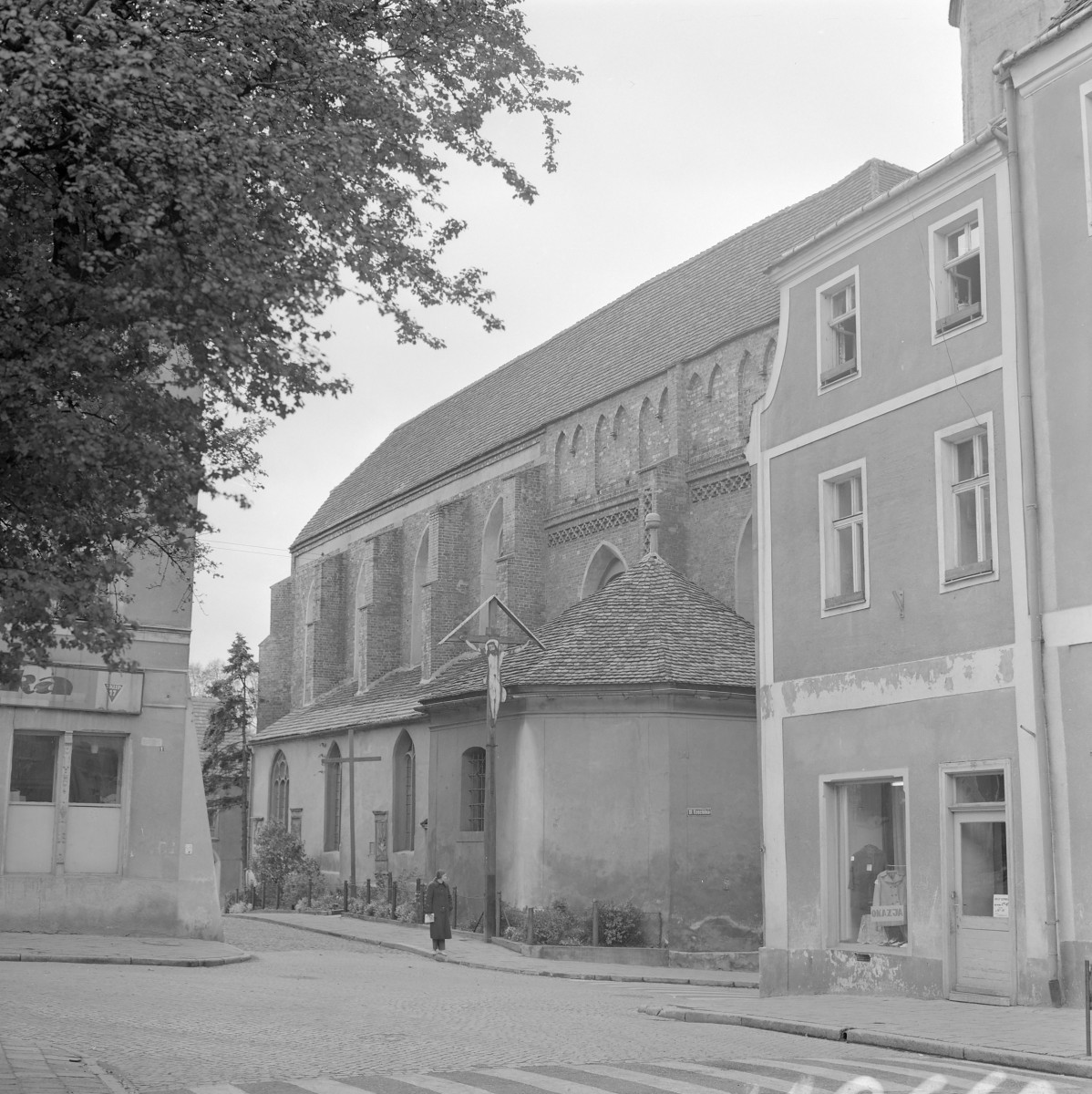 Kościół parafialny Oczyszczenia NMP - elewacja boczna z widoczną absydą oraz przyporami nawy głównej. Obok fragmenty zabudowy miejskiej - kamienice., skan 1