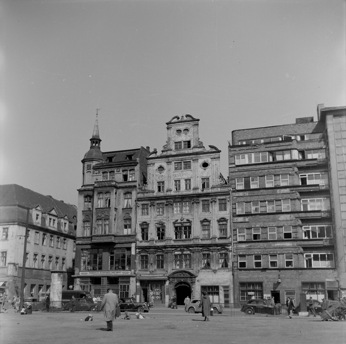 Pierzeja. Kamienica po lewej stronie z eklektycznymi elementami secesji. Widoczny wykusz nad parterem. Narożna wieżyczka z hełmem. Środkowa kamienica w stylu barokowym. Barokowy szczyt z wolutami i owalnymi oknami. Widoczny portal bramny. kamienica po prawej stronie to już styl modernistyczny. Proste okna, brak dekoracji. Przed kamienicami zaparkowane przedwojenne samochody., skan 1