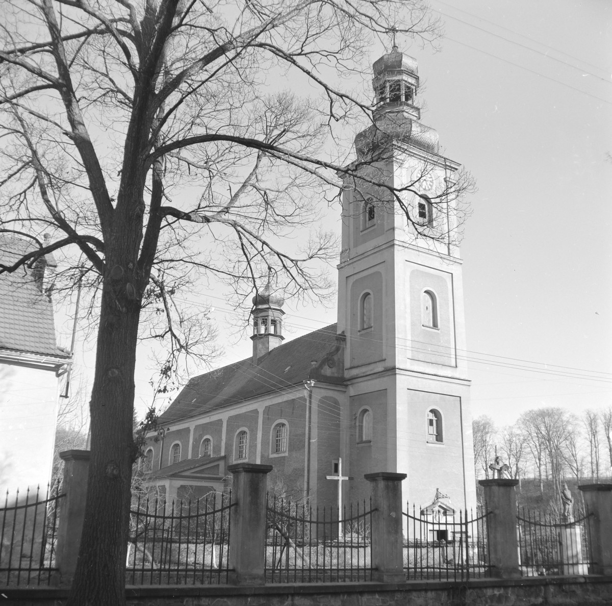 Kościół św. Piotra i Pawła - front wraz z wieżą z cebulastym hełmem i latarnia. Widoczny portal wejściowy i ogrodzenie., skan 1