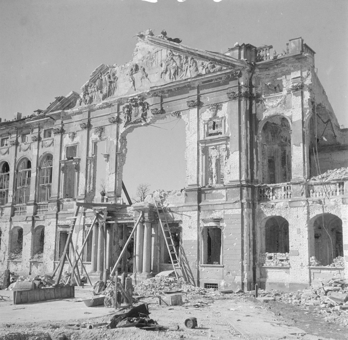 Pałac Krasińskich. Zniszczony korpus główny wraz z fasadą. Zniszczony trójkątny fronton oraz tympanon z płaskorzeźbą Andreasa Schlütera "Pojedynek Waleriusza z wodzem Gallów". Potężny otwór w elewacji frontowej. Początek odbudowy., skan 1