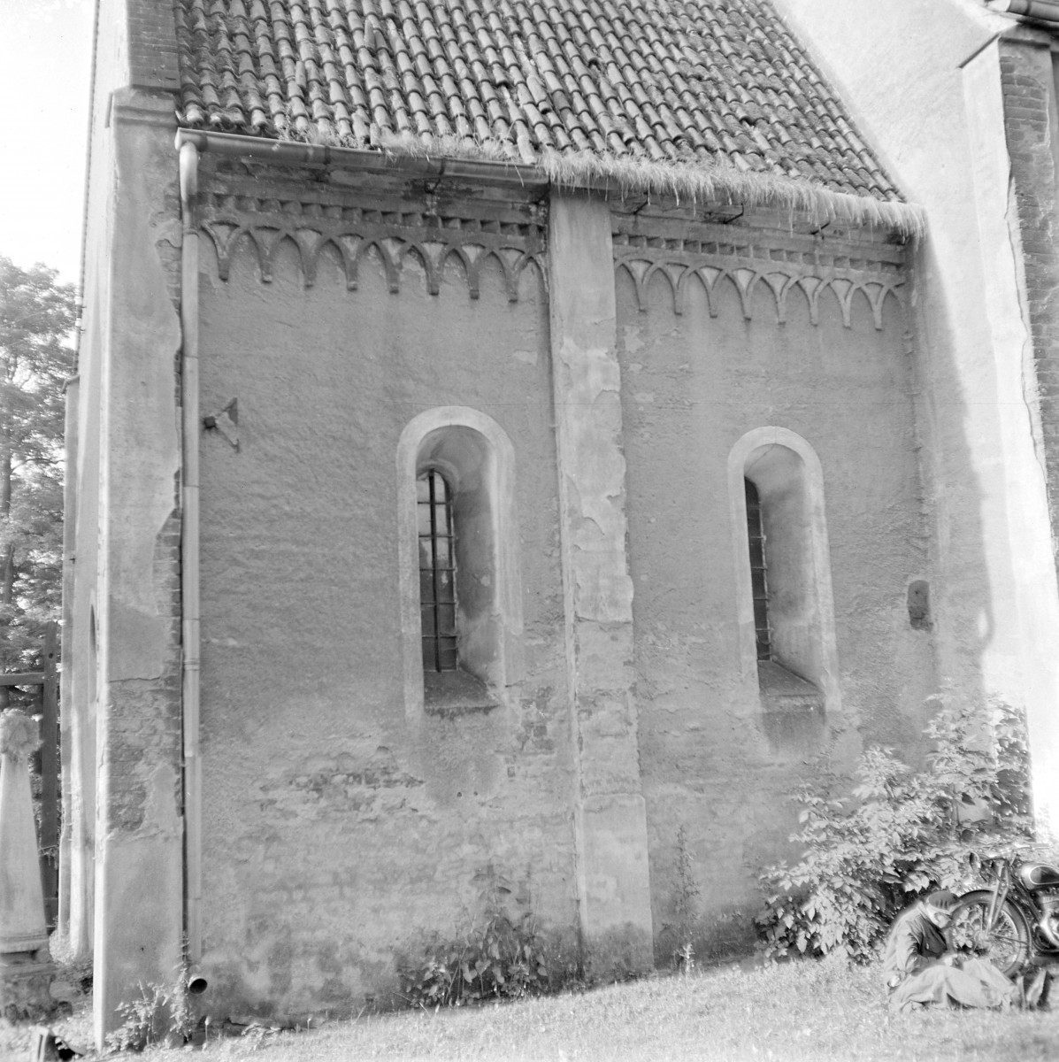 Kościół Świętego Krzyża. Fragment prezbiterium. Fryz arkadkowy, wykonany w cegle. Tworzy go rytmiczny ciąg niewielkich, ostrołukowych blend wspartych na drobnych wspornikach, co nadaje elewacji dekoracyjny, a zarazem archaiczny charakter. Wąskie, wysokie okna o ostrołukowym zamknięciu i głębokich rozglifieniach. , skan 1