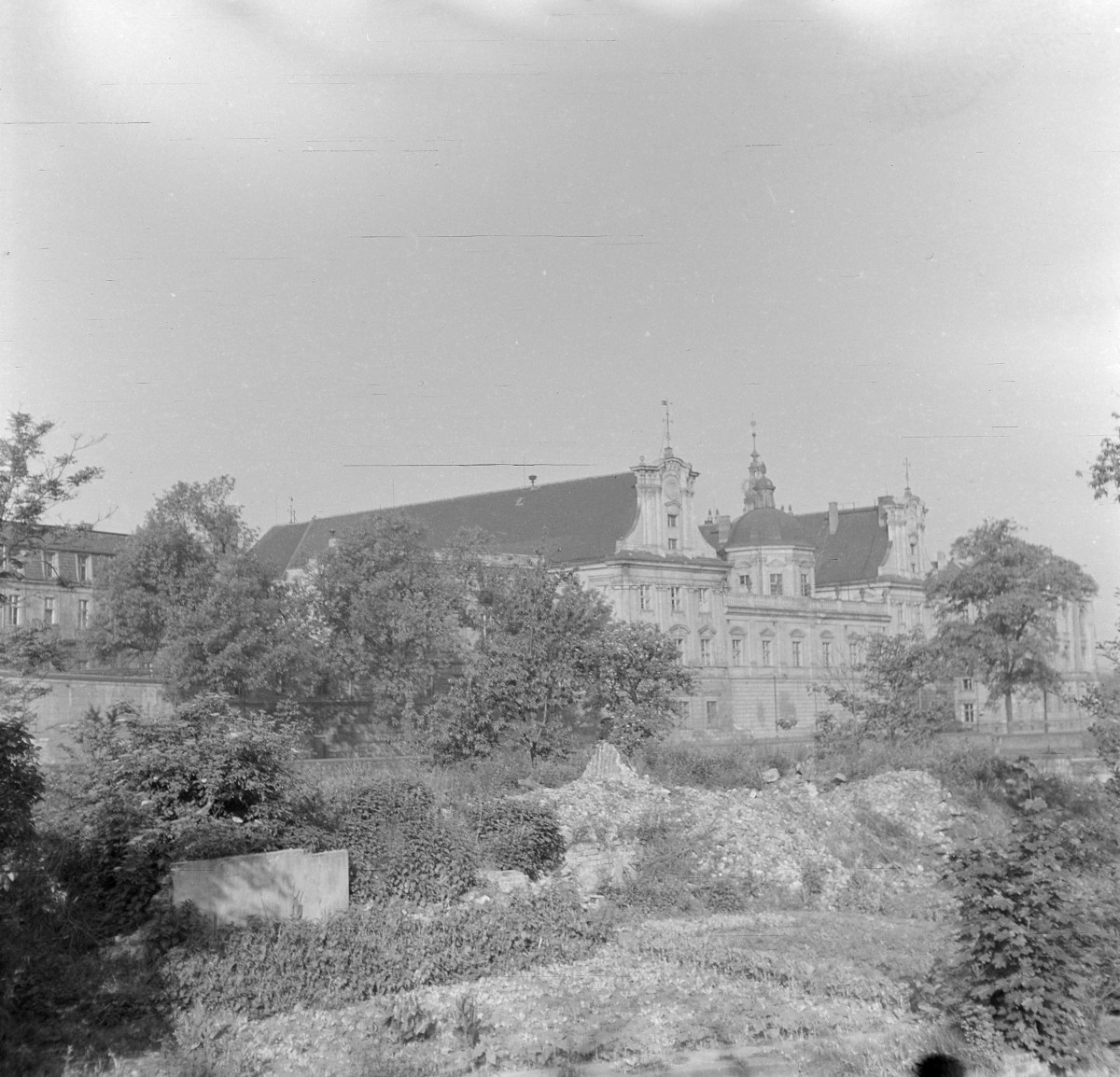 Klasztor Szpitalników z Czerwoną Gwiazdą. Szerokie ujęcie. Rozległy wieloskrzydłowy kompleks. Elewacja głównego skrzydła jest monumentalna i osiowa, o wyraźnym podziale horyzontalnym zaznaczonym gzymsami. Środkową partię akcentuje kopuła osadzona na tamburze, zwieńczona latarnią i hełmem z krzyżem. Po obu stronach korpusu widoczne są ryzality zwieńczone ozdobnymi szczytami o bogatej, falistej linii, charakterystycznej dla śląskiego baroku. Otwory okienne rozmieszczone są rytmicznie, w regularnych osiach. , skan 1