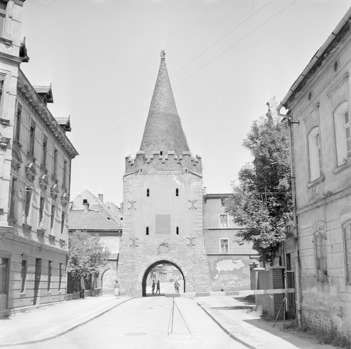 Brama Paczkowska.Górna część wieży zwieńczona jest krenelażem (zębatym zwieńczeniem murów), nad którym wznosi się wysoki, stożkowy dach pokryty dachówką. Smukły hełm zakończony jest ozdobnym zwieńczeniem. Całość nadaje budowli charakter typowej wieży bramnej o funkcji obronnej i kontrolnej. Brama wkomponowana jest w ciąg zabudowy miejskiej – po obu stronach znajdują się kamienice o elewacjach z przełomu XIX i XX wieku. Ulica prowadzi bezpośrednio pod łuk przejazdu, a w tle widoczne są kolejne zabudowania., skan 1