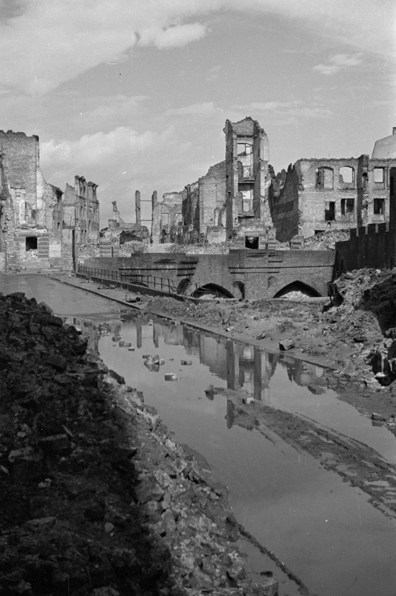 Zniszczona zabudowa miejska w okolicy mostka przy barbakanie. Ruiny kamienic., skan 1