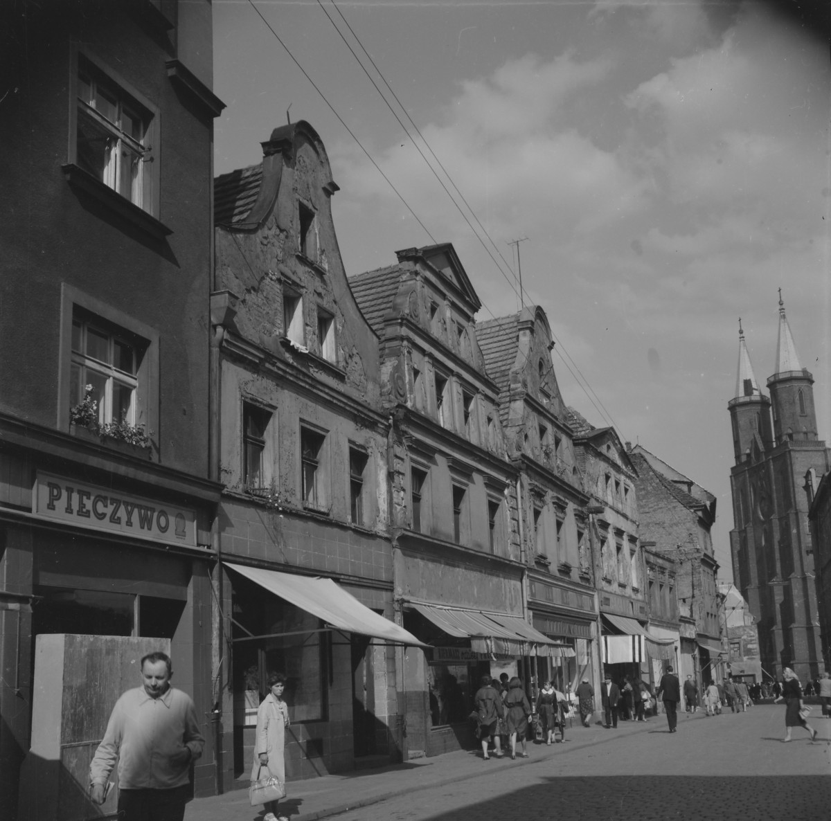 Zabudowa miejska. Oś widokowa w kierunku rynku. W oddali widoczne wieże kościoła Mariackiego. Pierzeja renesansowe. Witryny sklepów i mieszkańcy., skan 1
