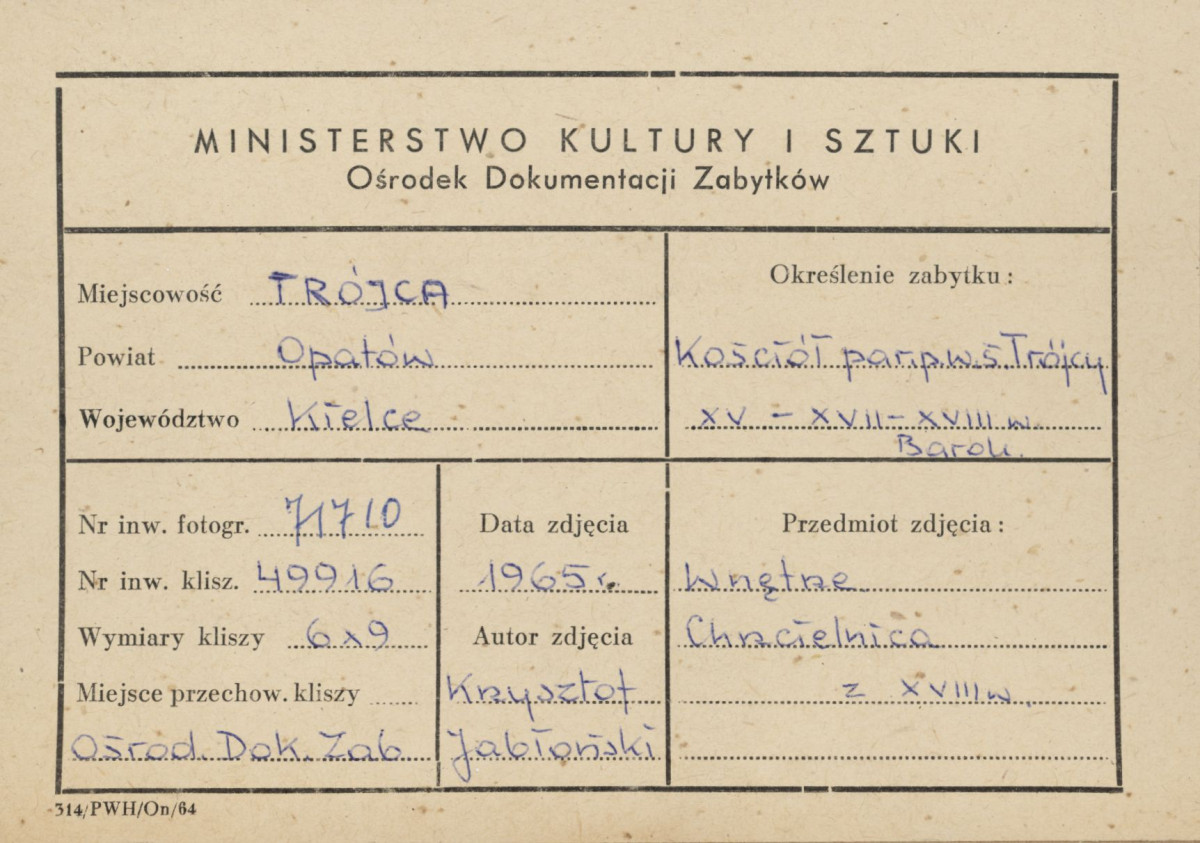 Kościół parafialny św. Trójcy -  wnętrze, widok na chrzcielnicę w snycerskiej obudowie - metryczka, skan 1