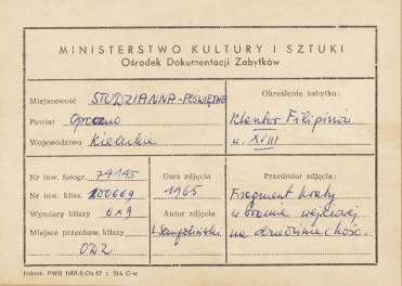 Zespół klasztorny Filipinów - fragment kraty bramy głównej z monogramem i datą, w tle szczyt fasady kościoła  - metryczka, skan 1