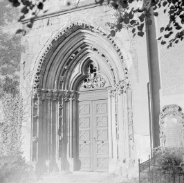 Kościół św. Mikołaja. Portal zachodni. Składa się on z kilku uskokowych ościeży, których krawędzie dekorowane są drobną ornamentyką – widoczne są ślady rzeźbionych detali roślinnych oraz niewielkich motywów figuralnych. Archiwolta ma wyraźnie warstwową konstrukcję, typową dla architektury gotyckiej. W polu tympanonu znajduje się niewielkie okno z maswerkiem o motywach trój- i czteroliścia, które doświetla przedsionek. Poniżej umieszczone są drewniane, dwuskrzydłowe drzwi z płycinami dekorowanymi prostym, geometrycznym ornamentem., skan 1