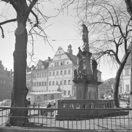 Rynek z zabudową miejską. Widoczna elewacja frontowa Ratusza. Na pierwszym planie figura wotywna Matki Bożej z Dzieciątkiem., skan 1